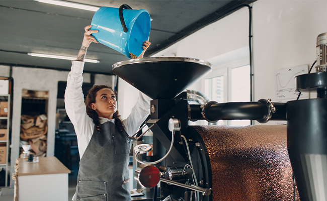 operator empties bucket into coffee roaster - bad ergonomics